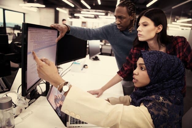 Diverse students working collaboratively on a coding project in a modern computer lab, showcasing teamwork and technological engagement.