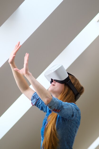 A student wearing a VR headset, hands gesturing in the air, immersed in a virtual classroom environment with interactive lessons floating around them.