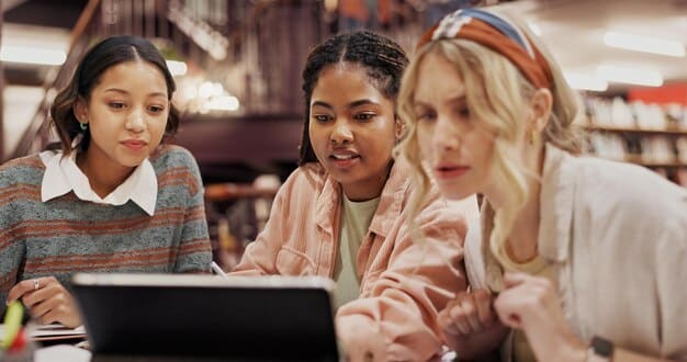 A diverse group of middle school students engaged in a digital citizenship class, attentively listening to a teacher who is pointing at a screen displaying concepts about online safety and well-being.