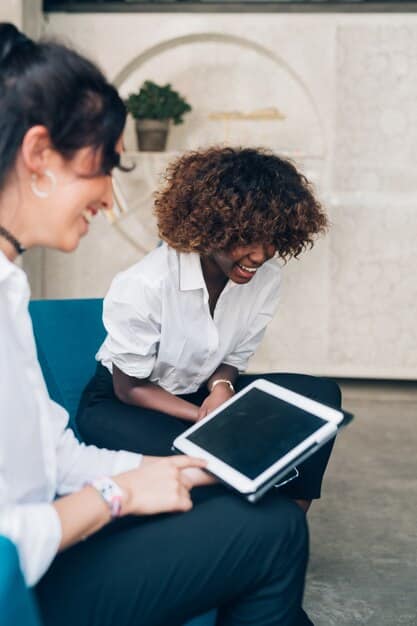 A school principal and a mental health counselor collaboratively discussing a school-wide policy document related to student well-being and responsible technology use, with a digital tablet showing policy guidelines in the foreground.