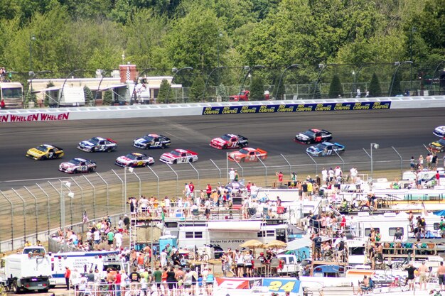 A packed grandstand cheering as Next Gen NASCAR cars race by on a banked oval, emphasizing the excitement and improved visual appeal of the new cars.