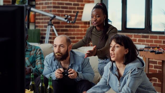 A diverse group of young adults, looking enthusiastic and engaged, gathered around a large screen displaying competitive video game action in a modern, collaborative setting.