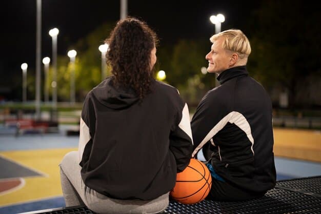 A veteran basketball player, deep in thought, offering advice to a younger teammate during a break in play, with a look of shared wisdom and guidance. The arena crowd is blurred in the background.