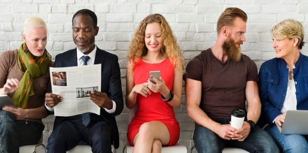 A diverse group of people – a mix of full-time employees and gig workers – collaborating around a table in a modern, open-plan office space. They are animatedly discussing ideas, with laptops open and whiteboards in the background, illustrating seamless integration and teamwork.