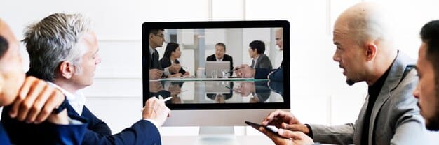 A professional looking at a laptop screen, engaging in a video conference with multiple participants, symbolizing virtual networking and global connectivity.