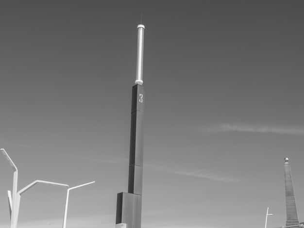 Industrial smoke stacks replaced by wind turbines and solar panels in a blurred background, with a foreground focus on a worker in a modern manufacturing plant utilizing automated machinery for clean energy component production. The scene suggests a transition from traditional to green manufacturing.