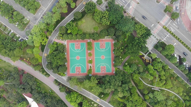 An aerial shot of multiple community sports fields and courts bustling with activity, showing children playing various sports like basketball, tennis, and track, illustrating widespread access and diverse program offerings.