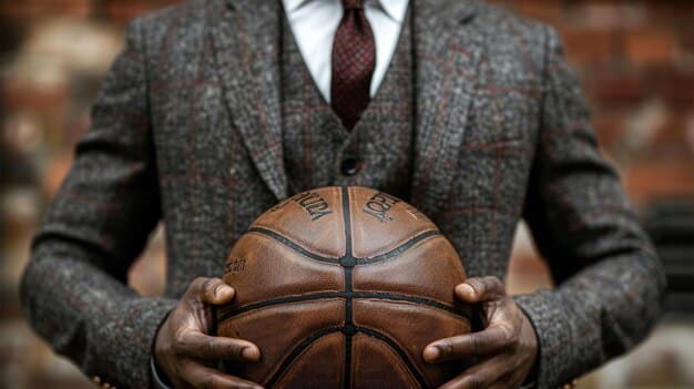 A detailed close-up photograph focusing on the signature of NBA Commissioner Adam Silver on the new Collective Bargaining Agreement. The document's text is visible but blurred, emphasizing the importance of this official act. The image is set against a backdrop of NBA team logos, reinforcing the league-wide impact of the agreement.